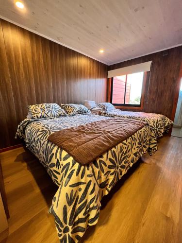 a large bed in a bedroom with a wooden wall at Hotel Boutique Family Suites in Panguipulli