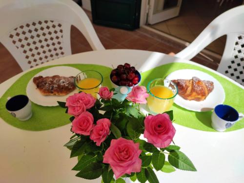 a table with roses and a bouquet of food and drinks at Sea Garden, fronte mare con piscina in Mascali