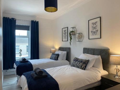 een slaapkamer met 2 bedden en een raam bij The Retreats 2 Kenfig Hill Pet Friendly 2 Bedroom Flat with King Size bed twin beds and sofa bed sleeps up to 5 people in Kenfig Hill