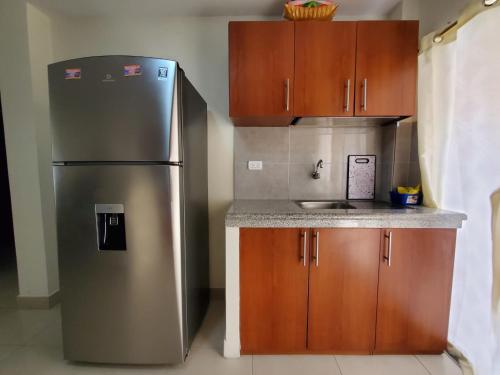 a kitchen with a stainless steel refrigerator and wooden cabinets at Metrópolis Apartaments for Rent in Guayaquil