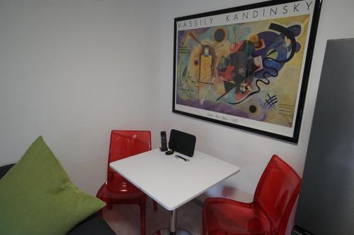 um quarto com uma mesa branca e cadeiras vermelhas em Neue und zentral gelegene Wohnung in Stuttgart em Stuttgart
