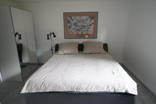 um quarto com uma cama grande e lençóis brancos em Neue und zentral gelegene Wohnung in Stuttgart em Stuttgart