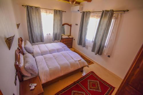 a bedroom with a bed in a room with windows at Kasbah Roseville in Ait Sedrate Sahl Gharbia