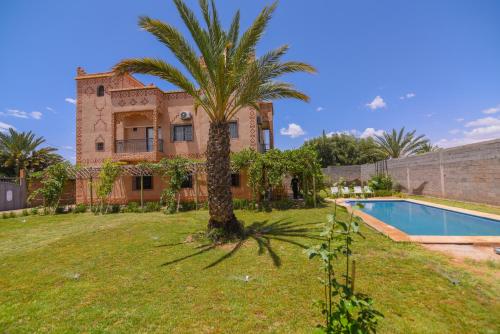 ein Haus mit einer Palme und einem Pool in der Unterkunft Kasbah Roseville in Aït Ouahi