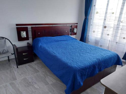 a bedroom with a bed with a blue comforter at Acogedor apartamento La Nubia in Manizales