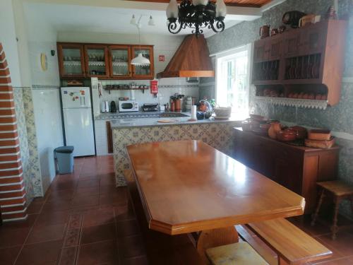 a kitchen with a wooden table and a refrigerator at Casa da Marcolininha in Vieira do Minho