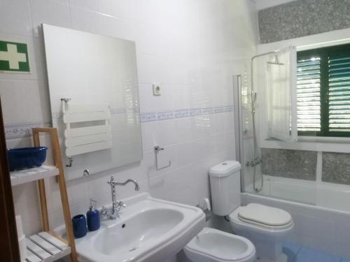 a white bathroom with a sink and a toilet at Casa da Marcolininha in Vieira do Minho