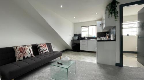 a living room with a black couch and a kitchen at Lovely 2 Bed Apartment by YO ROOM- Leicester City- Free Parking in Leicester