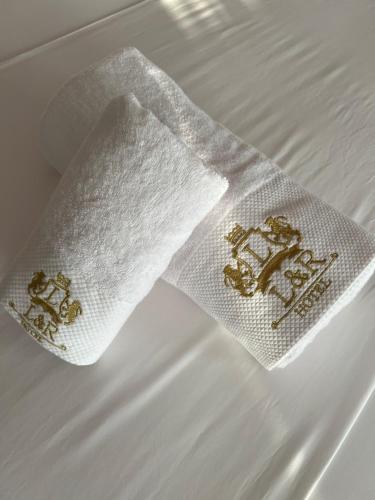 a white napkin with gold embroidery on a bed at Hotel LEON - Beach Front in Shëngjin