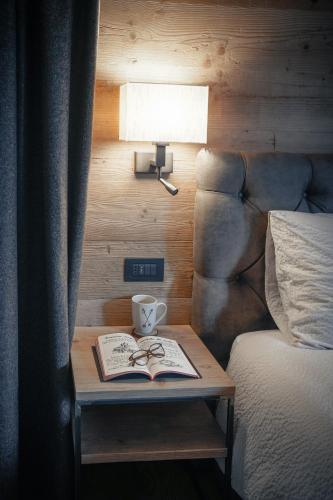 a bed with a table with a book and a cup and a lamp at Sci Sport rooms & suites in Bormio