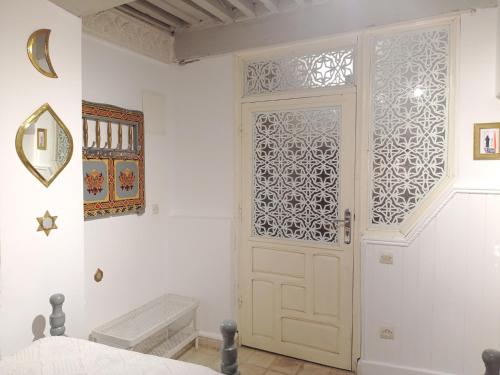 een witte kamer met een deur en een raam bij Dar Azahara in Fès