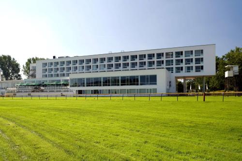 ein großes Gebäude mit einem Feld davor in der Unterkunft Atlantic Hotel Galopprennbahn in Bremen