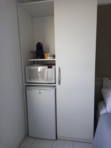 a small kitchen with a microwave and a refrigerator at Acomodação aconchegante à beira- mar in Natal