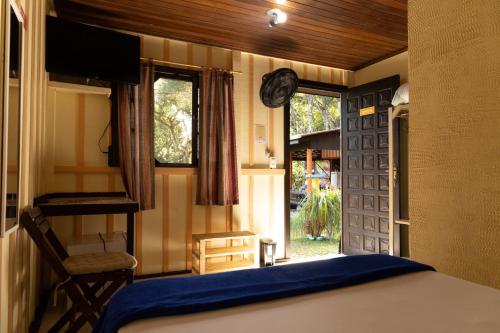 1 dormitorio con 1 cama y puerta con ventana en Pousada Recanto das Cores, en Ilha do Mel