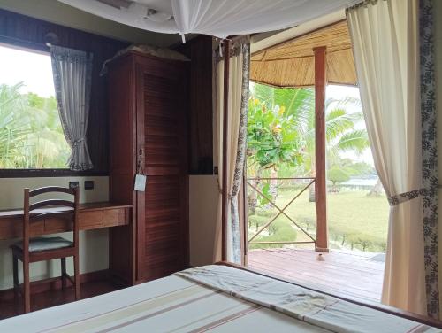 1 dormitorio con cama, escritorio y ventana en La Tiaré île aux Nattes en Isla Santa María