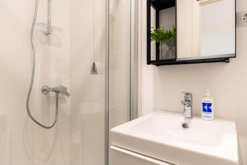 a white bathroom with a sink and a shower at Urban Condo in Liepāja