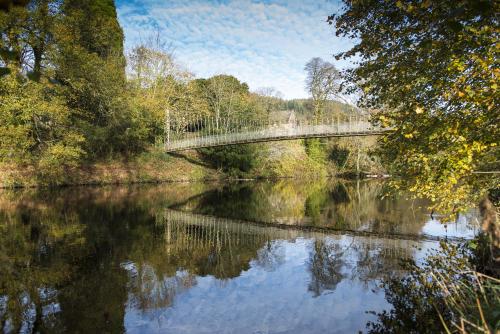 a bridge over a river with trees and water at The Courthouse in Betws-y-coed