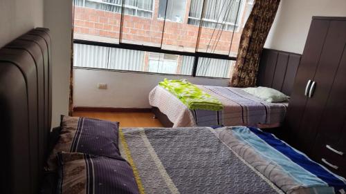 Cette petite chambre comprend 2 lits et une fenêtre. dans l'établissement WASYCHACUSCO, à Cusco