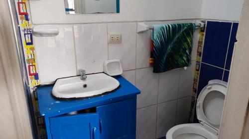 La salle de bains est pourvue d'un lavabo bleu et de toilettes. dans l'établissement WASYCHACUSCO, à Cusco