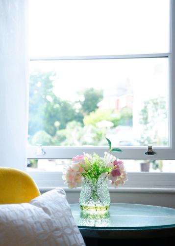 a vase of flowers on a glass table in front of a window at Gresham Court in Torquay