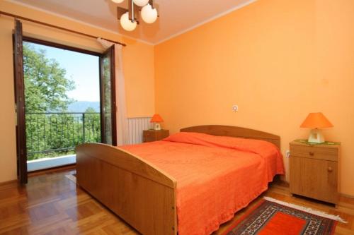 1 dormitorio con cama de color naranja y ventana grande en Holiday house with a parking space Krsan - Vlasici, Central Istria - Sredisnja Istra - 7685, en Kršan