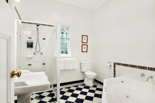 a white bathroom with a sink and a toilet at The Bundanoon Guest House in Bundanoon