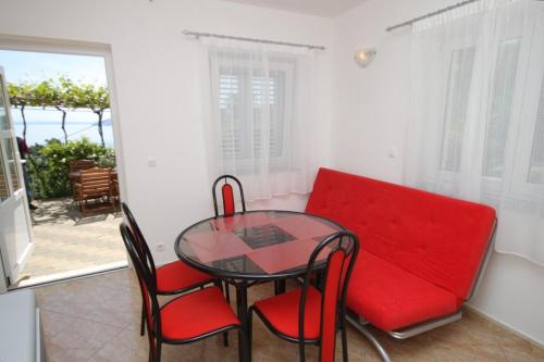 a dining room with a red couch and a glass table at Apartments with a parking space Medveja, Opatija - 7721 in Medveja