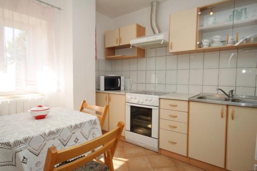 a kitchen with a table and a sink and a stove at Holiday house with a parking space Veprinac, Opatija - 7699 in Veprinac