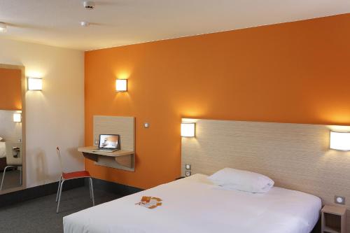 a hotel room with a bed and an orange wall at B&B HOTEL Gap in Gap