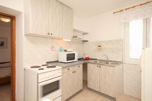 a white kitchen with a stove and a microwave at Holiday apartments Osor, Losinj - 8004 in Nerezine