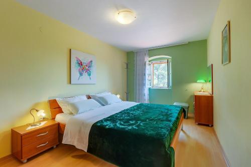 a bedroom with a large bed with a green blanket at Apartments and rooms with parking space Nerezine, Losinj - 8049 in Nerezine