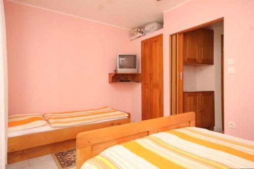 a bedroom with two beds and a tv on the wall at Apartment Susak 8047a in Susak