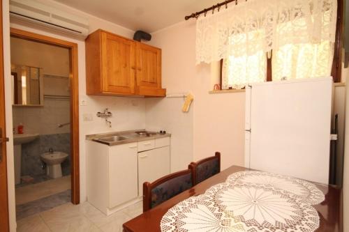 een keuken met een tafel, een wastafel en een koelkast bij Apartment Susak 8047a in Susak