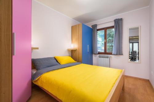 um quarto com uma cama amarela e azul e uma janela em Apartments with a parking space Lovran, Opatija - 7869 em Lovran