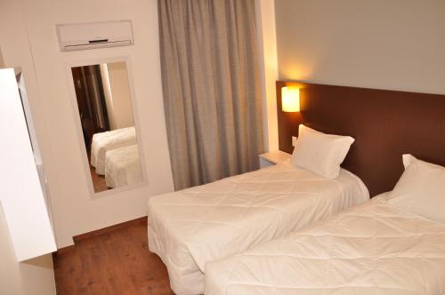 a hotel room with two beds and a mirror at Hotel Ipê MS in Campo Grande