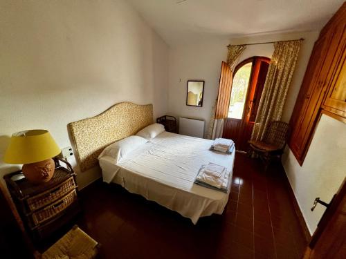 1 dormitorio con cama, lámpara y ventana en Villa fantastica Villasimius, en Capitana