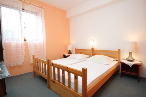 木洛希尼的住宿－Apartments and rooms by the sea Mali Losinj (Losinj) - 7977，一间卧室设有一张木床和一个窗户。