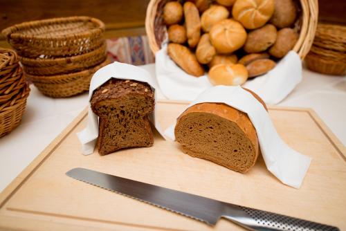 two slices of bread on a cutting board with a knife at Hotel Garni Doris in Castelrotto