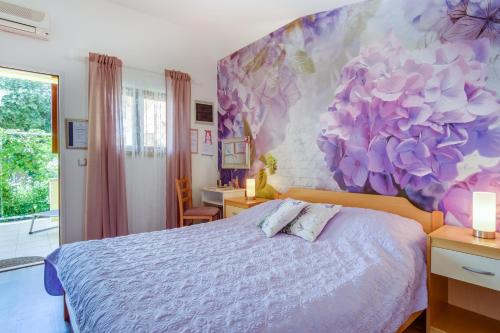 una camera da letto con un letto e un murale floreale sul muro di Apartments by the sea Artatore, Losinj - 7952 a Čunski