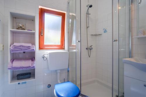 uma casa de banho com um chuveiro e um WC azul em Apartments by the sea Artatore, Losinj - 7952 em Čunski