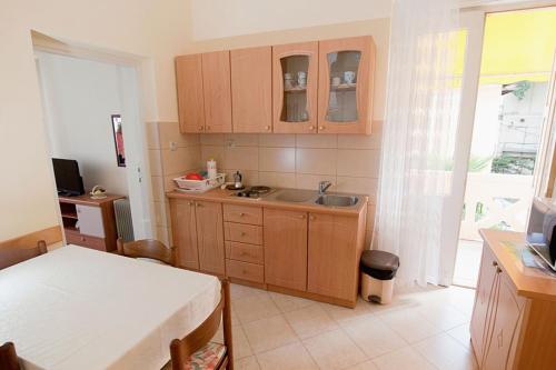 cocina con armarios de madera, fregadero y mesa en Apartments by the sea Lovran, Opatija - 7708 en Lovran