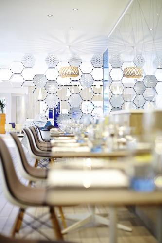 a dining room with tables and chairs and a tile wall at Novotel Manchester Centre in Manchester