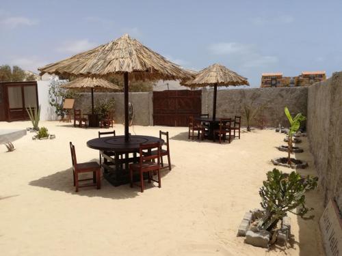 a group of tables and chairs with umbrellas on the beach at Vilas na areia aparthotel in Sal Rei