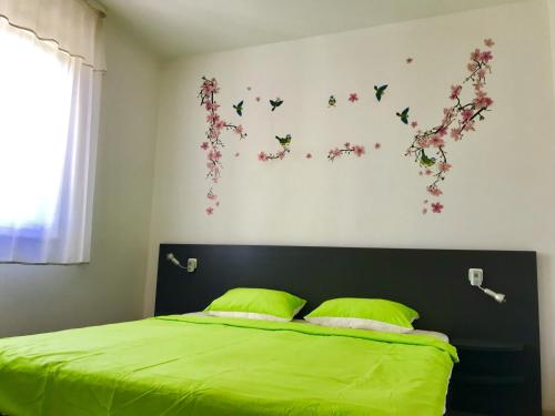 a bedroom with a bed with green sheets and butterflies on the wall at Apartments with a parking space Icici, Opatija - 7761 in Ičići