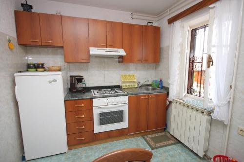 a kitchen with wooden cabinets and a white stove top oven at Apartments with a parking space Icici, Opatija - 7788 in Ičići