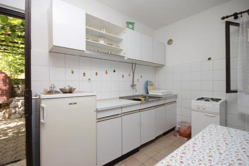 a white kitchen with white cabinets and a sink at Apartments with a parking space Icici, Opatija - 7763 in Ičići