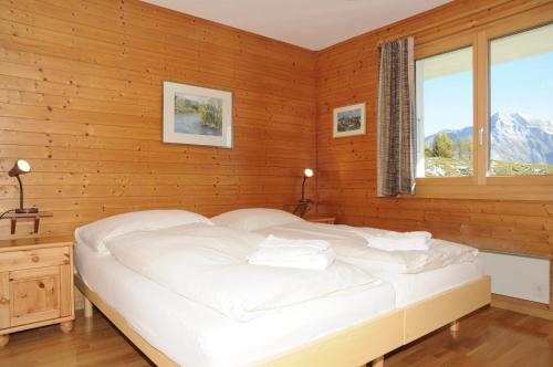 een slaapkamer met een wit bed en een raam bij Favorite Parterre in Riederalp