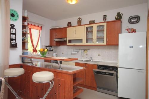 a kitchen with wooden cabinets and a white refrigerator at Apartments with a parking space Icici, Opatija - 7793 in Ičići