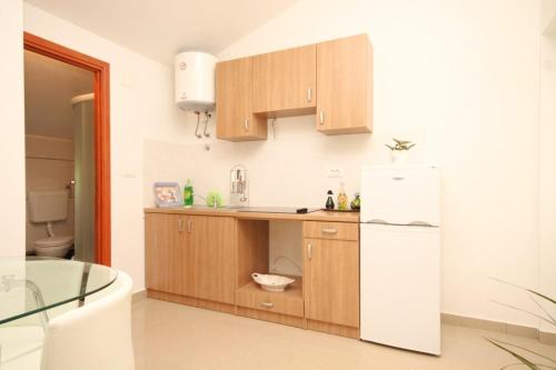a kitchen with wooden cabinets and a white refrigerator at Apartments with a parking space Opatija - 7891 in Opatija