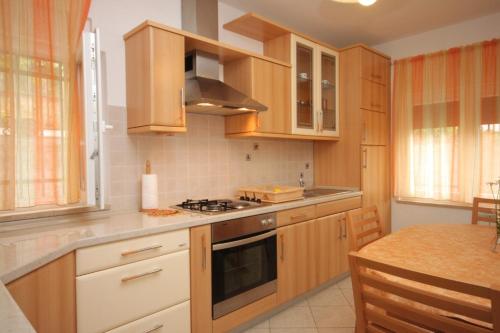 a kitchen with wooden cabinets and a stove top oven at Apartments with a parking space Opatija - 7857 in Opatija